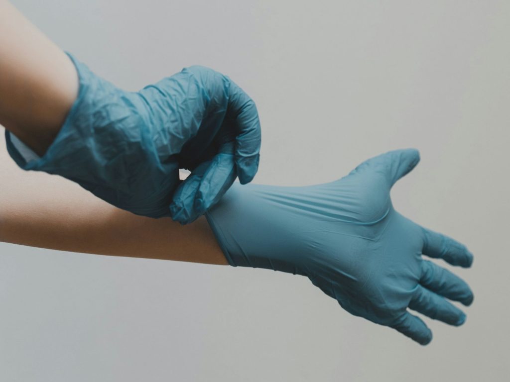 Doctor pulling on gloves as an operational AI forecasting model developed by Hertfordshire University researchers aims to improve resource efficiency within healthcare.